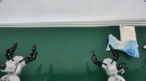 Robot grippers over a green work surface with a parcel