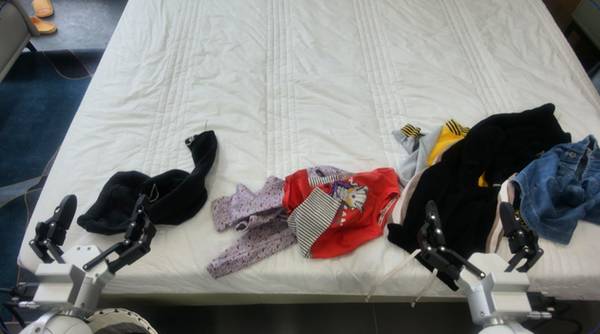 Dual-arm robot folding clothes on a bed