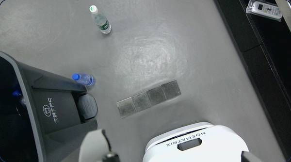 Overhead view of a robot near a bottle on the floor